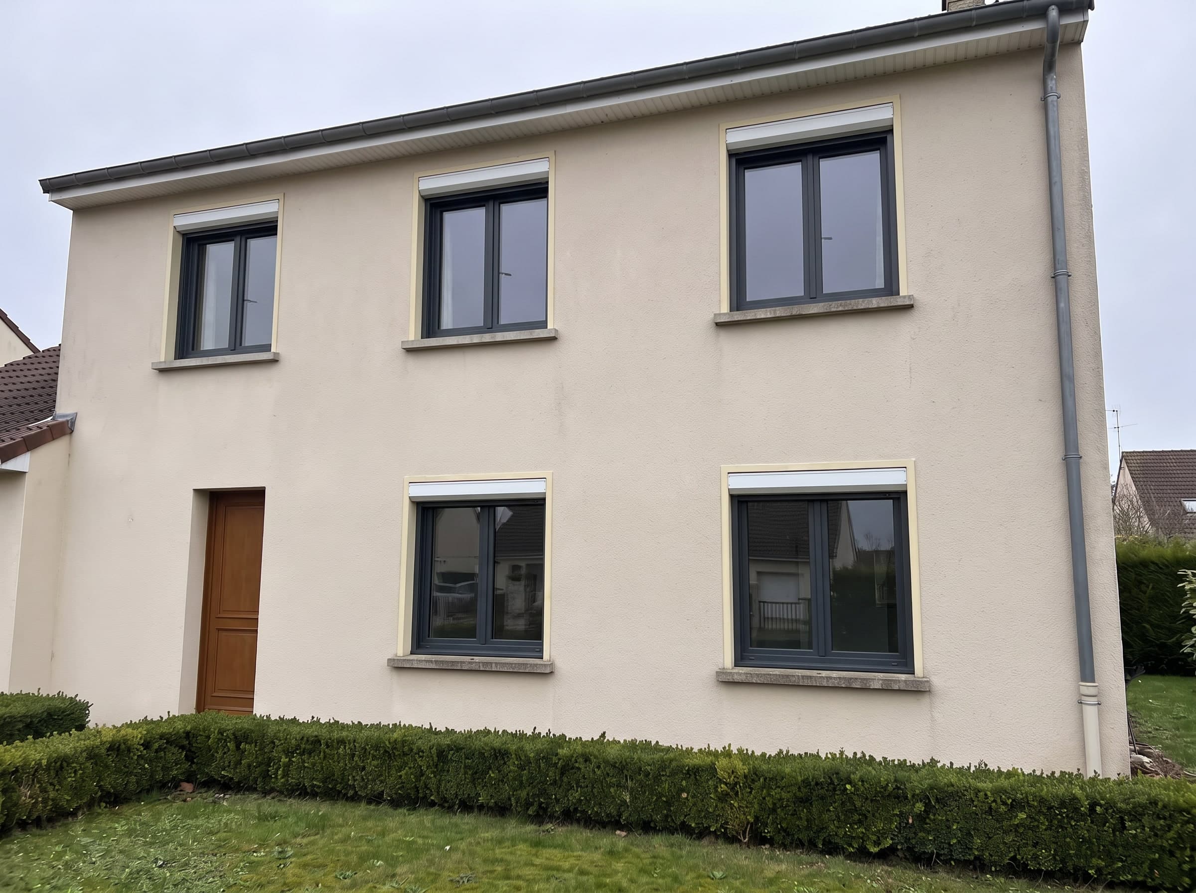 Dieselbe Fassade mit Fenstern aus anthrazitgrauem Aluminium mit zwei großen Flügeln, ohne Sprossen