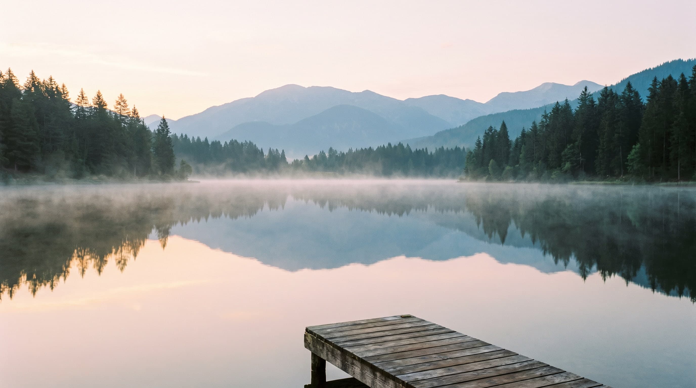 Der Bergsee im Morgenlicht, Nebel über dem Wasser und ein Holzsteg