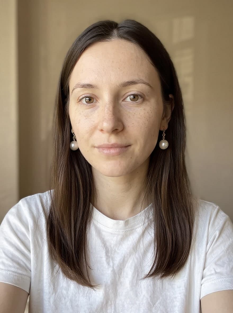 The same woman wearing white pearl drop earrings under a small gold link