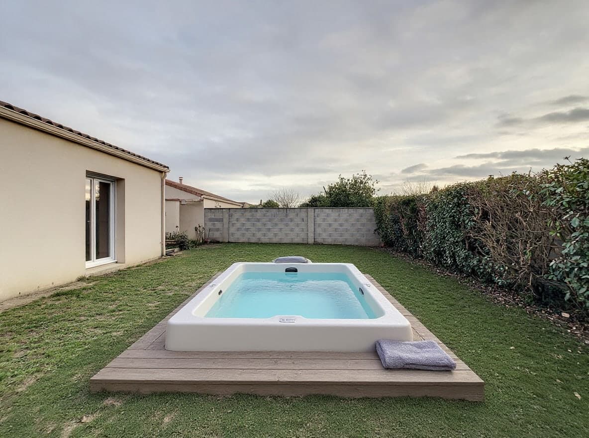 Derselbe Garten mit einem weißen Whirlpool mit türkisfarbenem Wasser auf einer kleinen Holzterrasse