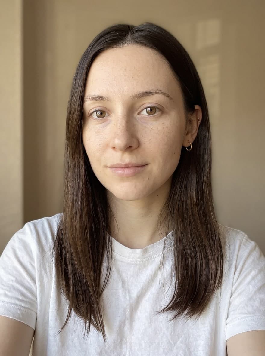 The same woman, hair tucked behind her ear, with a small gold stud and hoop