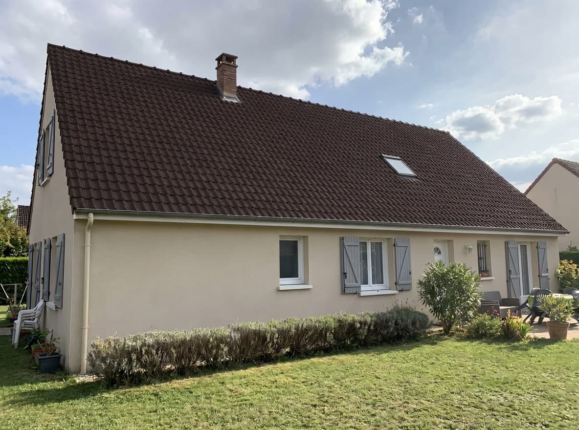 Dasselbe Haus mit dunkel schokoladenbraunen Ziegeln, Schornstein und Dachfenster an ihrem Platz