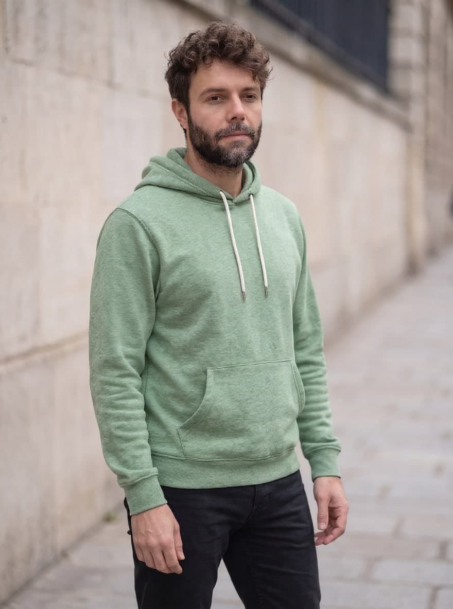 Derselbe Hoodie in gräulichem Salbeigrün, gleiche Person und gleiche Straße